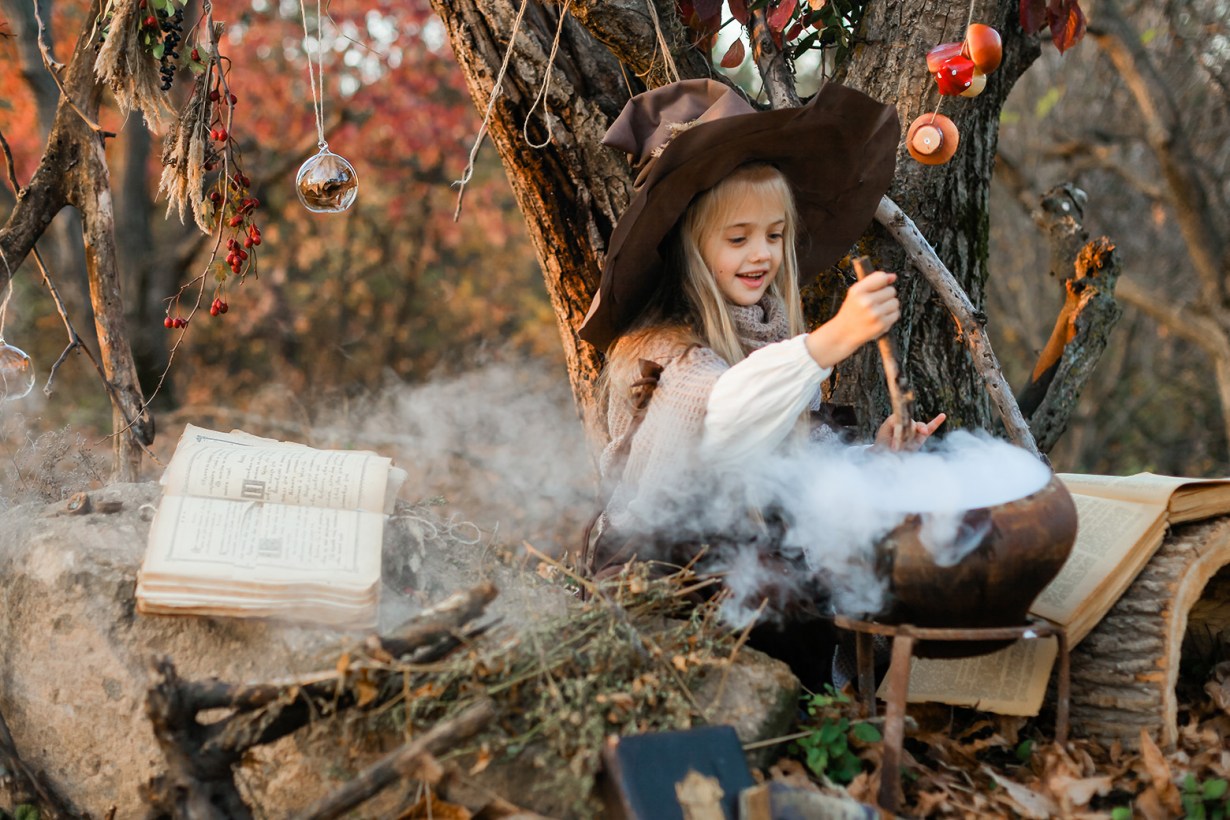 a little girl in a witch costume and witch props