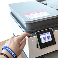 Person pressing power button on printer